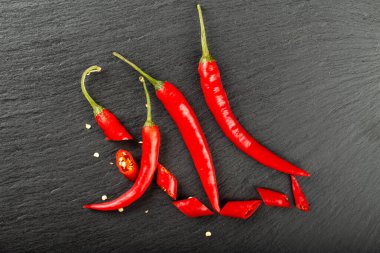 Siyah tahtada kırmızı ve doğranmış biber var. Baharatlı yemek konsepti. Mesaj için yer var. Üst görünüm.