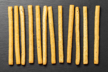 Siyah arka planda ev yapımı İtalyan Grissini Breadstix 'i. Bitkilerle geleneksel İtalyan atıştırması. Mesaj için yer var. Üst görünüm.