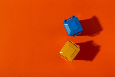 Turuncu arka planda mavi ve sarı renkli çöp konteynırları. Temizlik konsepti. Mesaj için yer var. Üst görünüm.