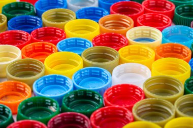 Beyaz arka planda bir sürü renkli plastik şişe kapağı. Geri dönüşüm kavramı.