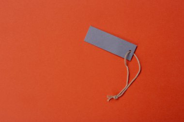 İple bağlanmış boş bir etiket. Fiyat etiketi, hediye etiketi, satış etiketi, turuncu arka planda izole edilmiş adres etiketi. Mesaj için yer var. Üst görünüm.