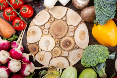 Tahta bir masanın üzerinde taze organik sebzeler sergileniyor. Ortasında yazı için yer var. Sağlıklı beslenme konsepti. Üst görünüm.