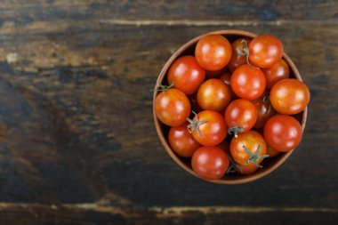 Kahverengi ahşap zemin üzerinde kiraz rengi domatesler. Yukarıdan görünüm