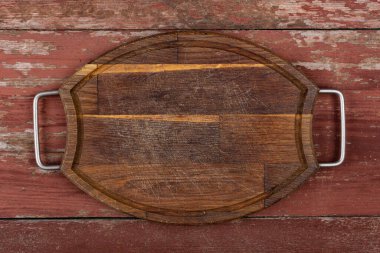 Boş oval kesme tahtası ve kırmızı ahşap bir masada demir sapları. Üst görünüm.