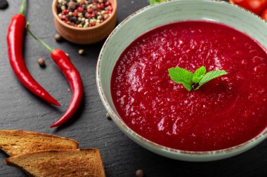 İştah açıcı yaz domates çorbası püre gazpacho siyah arka planda kasede servis edilir. Üst görünüm.