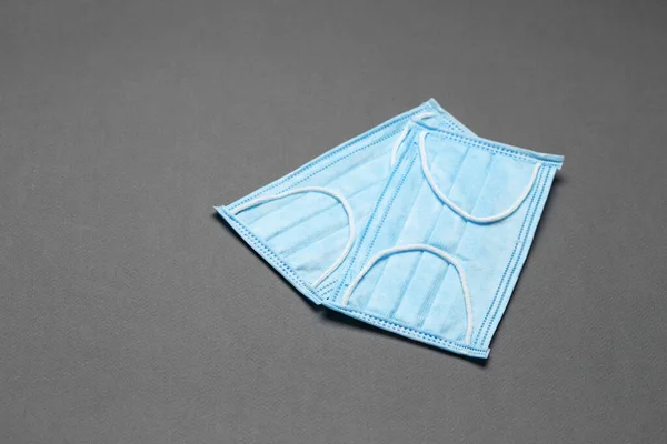 Surgical masks with rubber ear straps on a grey background. Typical 3-ply surgical mask to cover the mouth and nose. Procedure mask from bacteria. Top view.