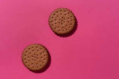 Tatlı çikolatalı kurabiyeler pembe arka planda düzgünce duruyordu. Üst görünüm.