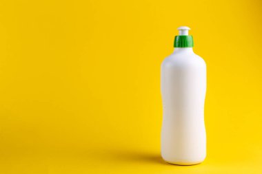 Sarı arka planda beyaz bir temizlik maddesi şişesi. Temizlik konsepti. Metin için boşluk.