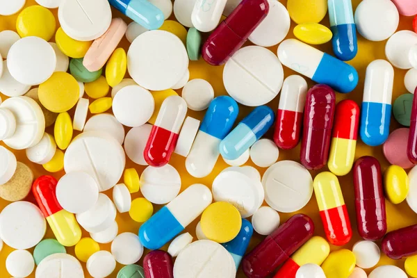 Sarı arka planda bir sürü farklı hap var. Tıbbi konsept. Çeşitli hastalık tehdidi kavramı. Üst görünüm.