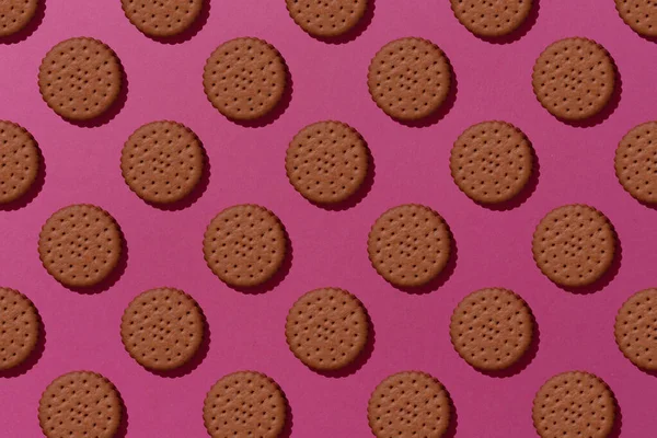 Tatlı çikolatalı kurabiyeler pembe arka planda düzgünce duruyordu. Üst görünüm.