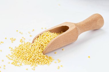 Millet, kaynamış lapa yapmak için beyaz arka planda ahşap bir kepçe..