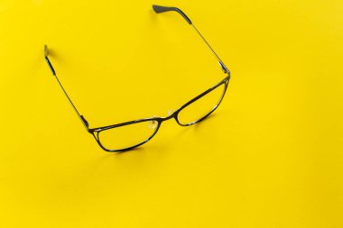 Sarı arka planda şık gözlükler. Sağlık, tarz ve iş konsepti. Görme düzeltmesi.