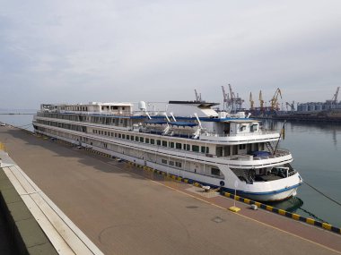 Bir yolcu gemisi arka planda yükleme ve boşaltma vinçleri olan bir rıhtıma demirlenir. Seyahat konsepti. Deniz Limanı