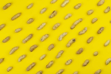 Sarı arka planda izole edilmiş yer fıstığı deseni. Tekrarlama konsepti. Üst görünüm