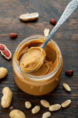 açık kavanozda fıstık ezmesi ve masaya dağılmış kabukta fıstık ezmesi.