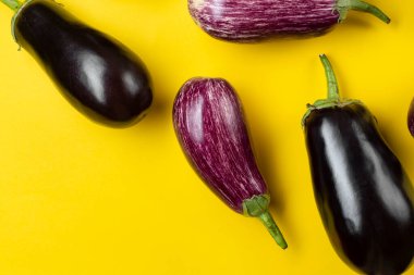 Sarı arka planda mor ve siyah patlıcan. Taze sebzeler. Üst görünüm.