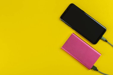 Smartphone Arkaplanda Güç Bankası ile şarj ediliyor. Mesaj için yer var. Üst Görünüm.