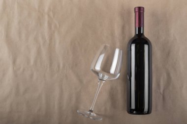 Kahverengi arka planda şarap şişesi ve cam. Şarap içme kültürü kavramı. Mesaj için yer var. Üst görünüm.