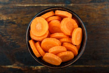 Ahşap arka planda bir kasede dilimlenmiş havuç. Sebze, malzeme ve zımba. Sağlıklı yemek..