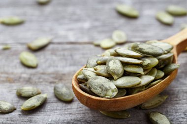 Tahta bir arka planda tahta kaşıkta kabak çekirdeği çekirdekleri.