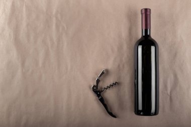 Kahverengi arka planda şarap şişesi ve tirbuşon. Mesaj için yer var. Üst görünüm.