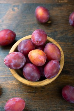 Masadaki ahşap kasede olgun erikler. Hasat mevsimi.
