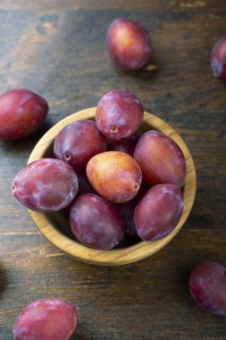 Masadaki ahşap kasede olgun erikler. Hasat mevsimi.