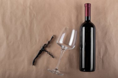 Kahverengi arka planda şarap şişesi, cam ve tirbuşon. Mesaj için yer var. Üst görünüm.