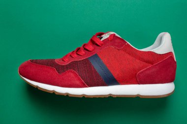 Yeşil arka planda yeni kırmızı spor ayakkabılar. Sıradan ayakkabılar. Mesaj için yer var. Üst görünüm.