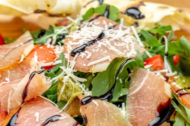 Domatesli taze salata, roka ve pastırma, üzerine parmesan peyniri serpiştirilmiş. Yakın plan..