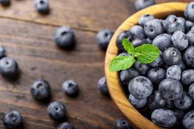 Tahta bir masada, ahşap kasede taze toplanmış yabanmersini. Sağlıklı meyve.