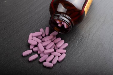 Pembe haplar, siyah arka plandaki cam bir kavanozdan etrafa saçılmış. Sağlık hizmeti konsepti. Mesaj için yer var. Muhafazakar tıp. Üst görünüm. 