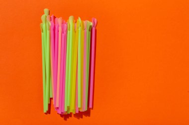 Turuncu arka planda pipet içmek. Kokteyl çubuğu. Boşluk