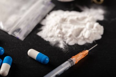 Siyah arka planda kokain ve diğer uyuşturucular, yakın plan. Uyuşturucu kullanımı için sarılmış bir dolar. Yasak uyuşturucular.