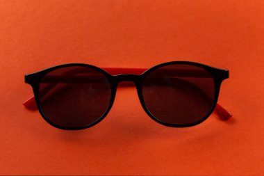 Turuncu arka planda katlanmış siyah güneş gözlüğü. Moda aksesuarları. Yaz mevsimi