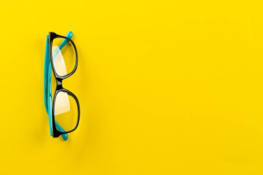 Sarı arka planda gözlük, miyop ya da prebyopia. Görme düzeltmesi. Moda aksesuarları. Mesaj için yer var. Üst görünüm.