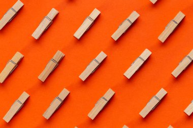 Turuncu arka planda birçok ahşap mandal var. Üst görünüm.