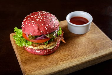 Kırmızı burger, pirzola ve tahta kesme tahtasında sebze. tex için yer