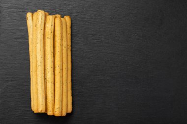 Siyah arka planda ev yapımı İtalyan Grissini Breadstix 'i. Bitkilerle geleneksel İtalyan atıştırması. Mesaj için yer var. Üst görünüm.