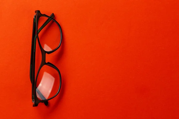 Stylish glasses for vision on an orange background. Fashion accessory. Ophthalmology theme. Space for text.