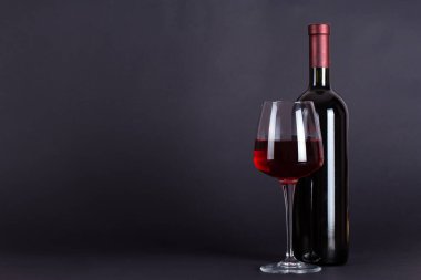 Eflatun bir arka planda mühürlü kırmızı şarap ve cam şişesi. Mesaj için yeri var. Şarap tatma ve içme kültürü konsepti. Alkolik içecek.