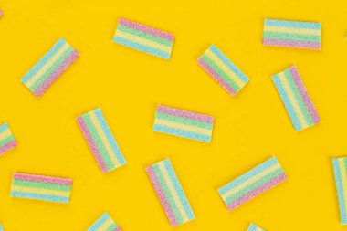 Sarı arka planda renkli şekerleme deseni. Yumuşak diş etleri yukarıdan görünüyor. Çeşitlilik konsepti. Eşcinsel renkleri. Tatlı yemek tatlısı. Yukarıdan görüntüle