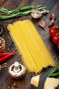 Taze domatesli çiğ makarna, biber, kuşkonmaz fasulyesi, baharat ve peynir ahşap bir masada. İtalyan spagettisi için yemek malzemeleri..