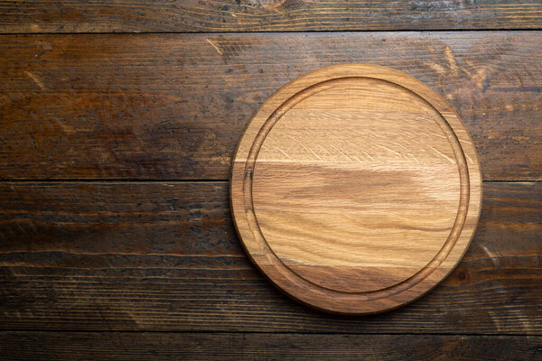 Empty round cutting board on a wooden table. Space for text. Top view.