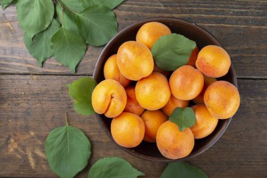 Masanın üzerindeki kil kasede leziz olgun kayısılar. Sağlıklı meyve.