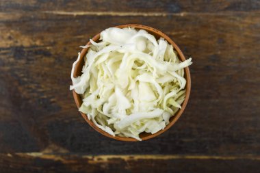 Ahşap arka planda bir kasede doğranmış lahana. Sebze, malzeme ve zımba. Sağlıklı yemek..