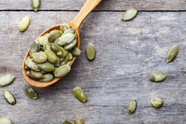 Tahta bir arka planda tahta kaşıkta kabak çekirdeği çekirdekleri.