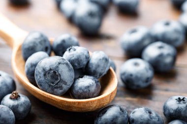 Tahta kaşıkta taze yaban mersini. Böğürtlenler ahşap bir masaya saçılmış. Vejetaryen ve vejetaryen kavramı. Antioksidan özelliği olan ürünler.