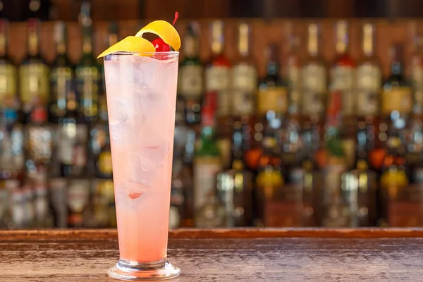 Barda muhteşem bir alkollü kokteyl. Bol buzlu pembe bir içecek, ve güzel bir limon kabuğu ve kiraz.
