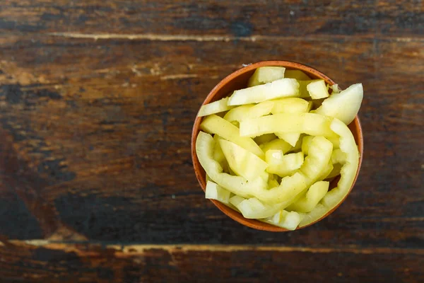 Ahşap arka planda bir kasede dilimlenmiş çiğ sarı biber. Sebze, malzeme ve zımba. Sağlıklı yemek..